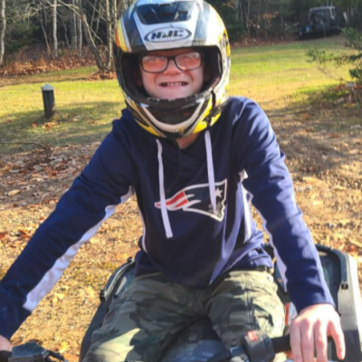 Joey Jordan smiles widely beneath his helmet while sitting on an ATV