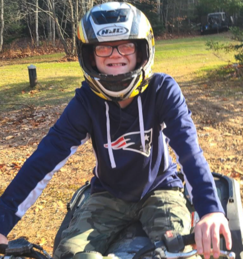 Joey Jordan smiles widely beneath his helmet while sitting on an ATV