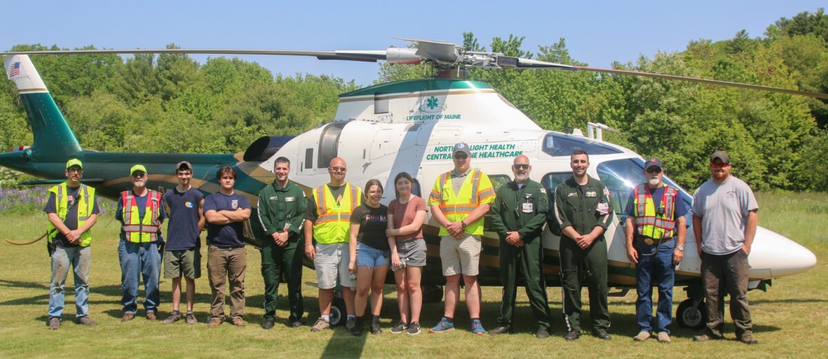 High school students and LoM staff pose in front of a LoM helicopter