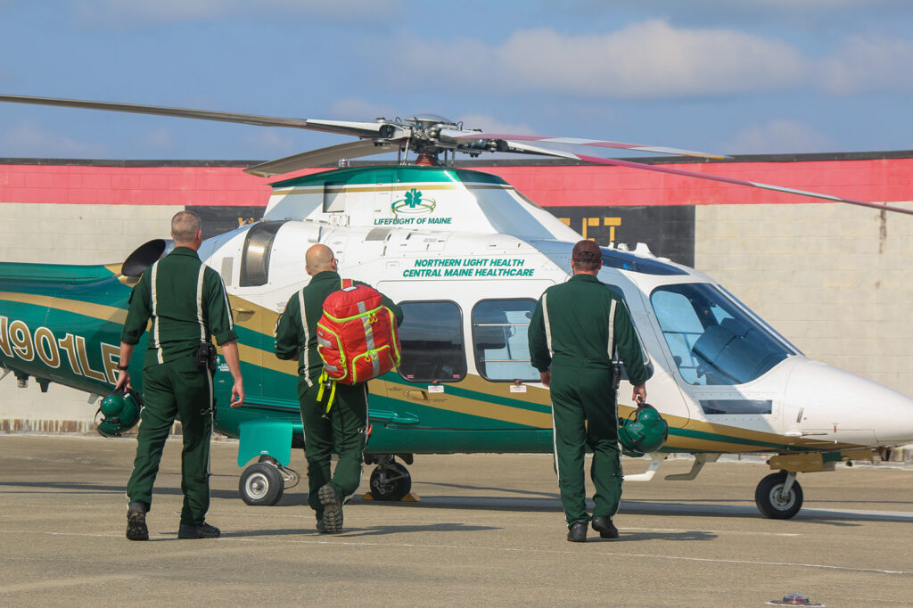 Three LifeFlight crew members walk toward a helicopter.