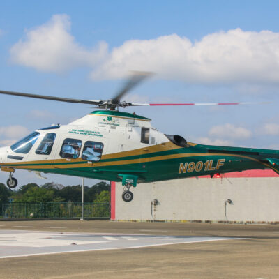 LifeFlight helicopter hovers above a hospital rooftop landing pad.