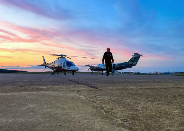 A LifeFlight pilot walks beside a helicopter and airplane